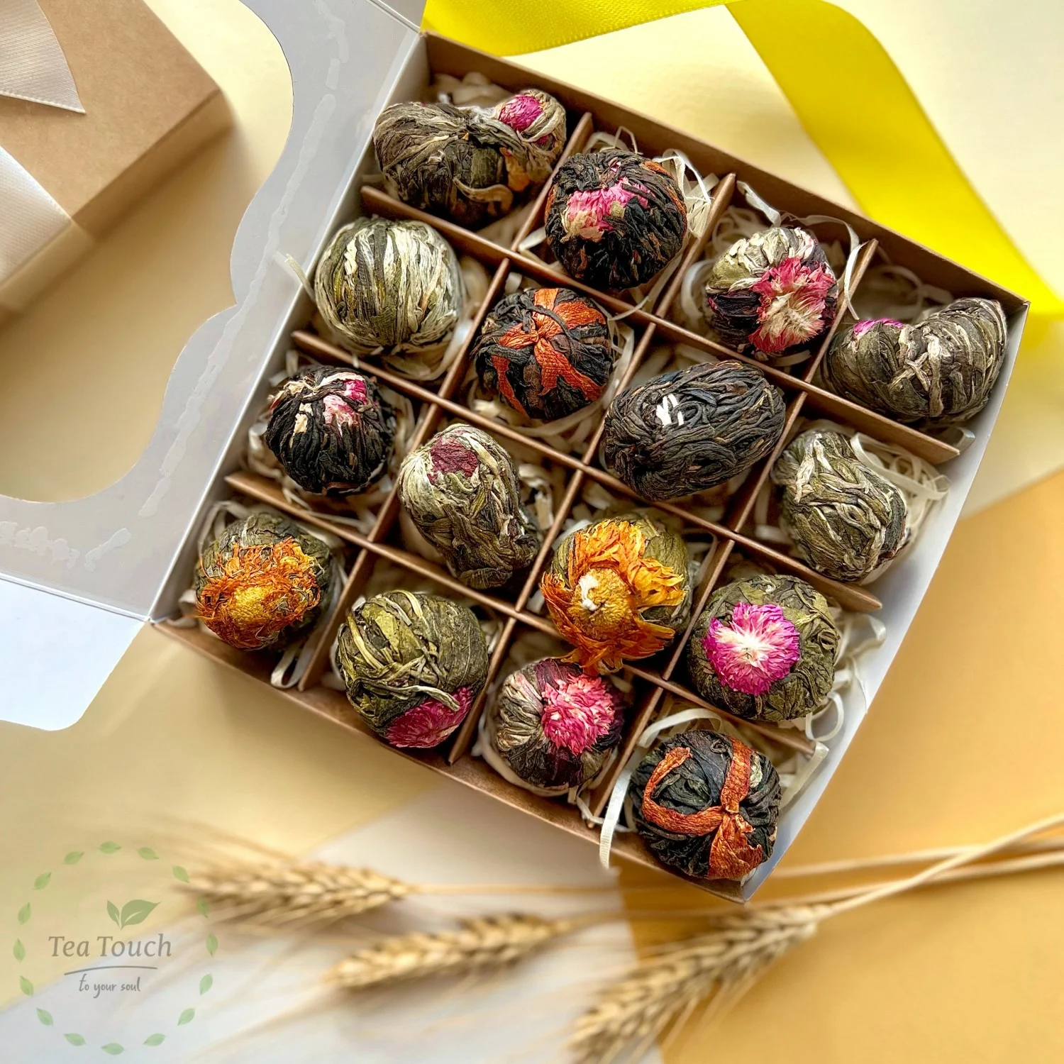 Blooming tea balls with pink blossom centres beside a cup of brewed tea